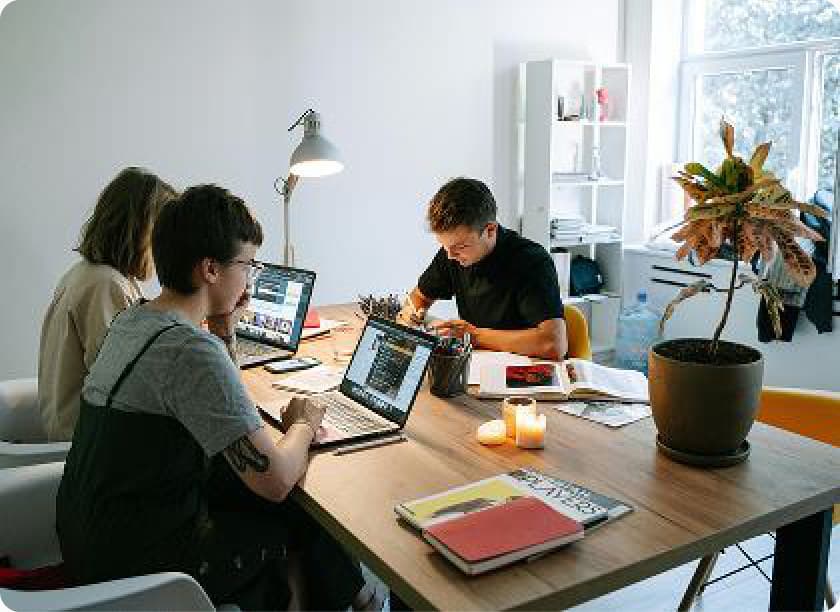 Members working at laptops around a shared desk